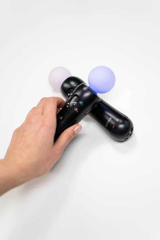 a person holding a video game controller in their hand, translucent orbs, detailed product image, 2 point lights, onyx