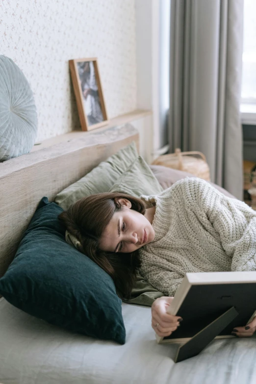 a woman laying in bed reading a book, a cartoon, pexels contest winner, cold mood, gif, low quality photo, reading nook