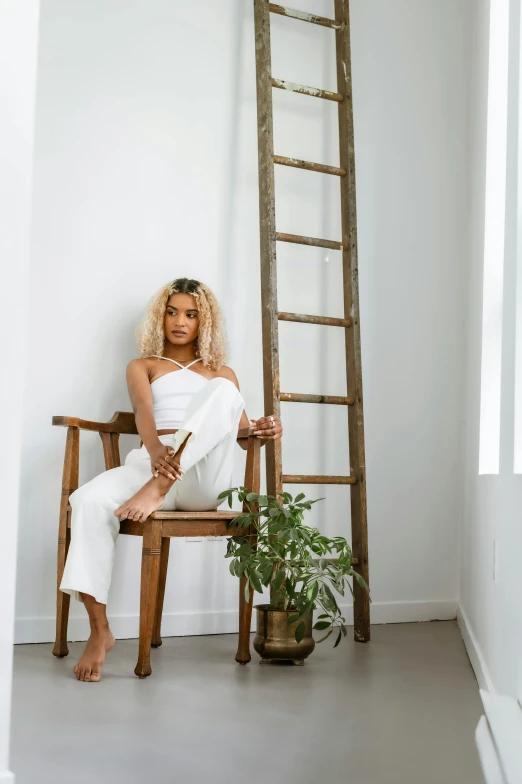 a woman sitting on a chair next to a ladder, by Dulah Marie Evans, all white, her hair is white, tessa thompson inspired, photoshoot for skincare brand