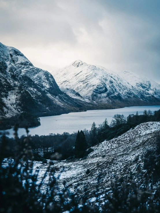 a large body of water surrounded by snow covered mountains, by Andrew Allan, unsplash contest winner, hurufiyya, harry potter series setting, glasgow, outside winter landscape, today\'s featured photograph 4k