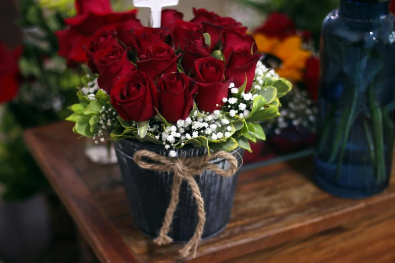 a vase filled with red roses and baby's breath, religious, rustic setting, dark hues, no cropping