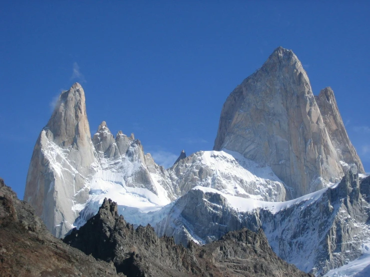 a group of snow covered mountains against a blue sky, by Matteo Pérez, pexels contest winner, tall stone spires, buenos aires, gray, graeme base