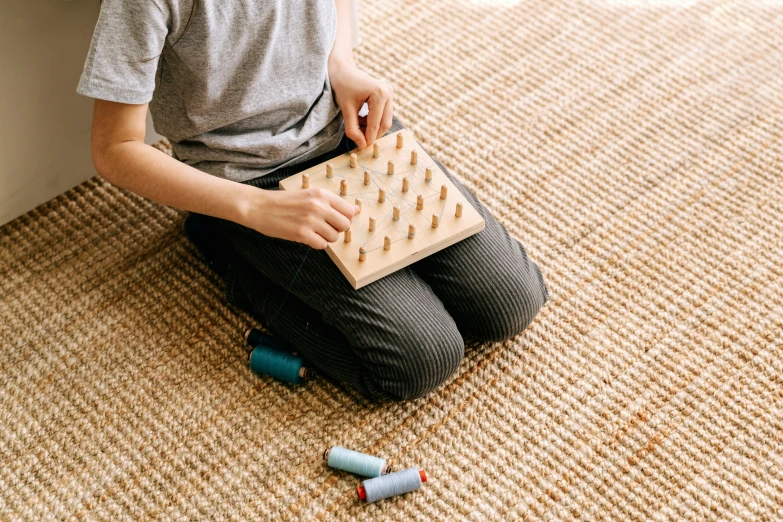 a little boy sitting on the floor playing with a board, inspired by Agnes Martin, trending on pexels, acupuncture treatment, corn chess board game, 1 6 x 1 6, fabric embroidery