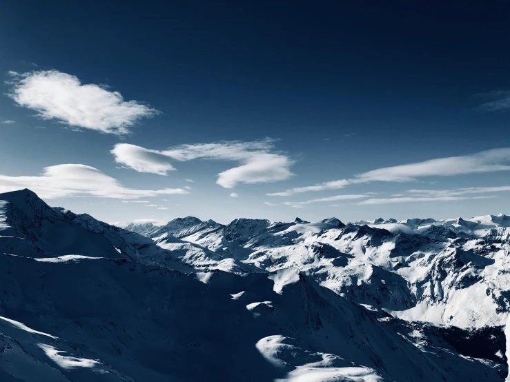 a man standing on top of a snow covered mountain, by Matthias Weischer, pexels contest winner, hurufiyya, blue hues, view from the sky, big sky, multiple stories