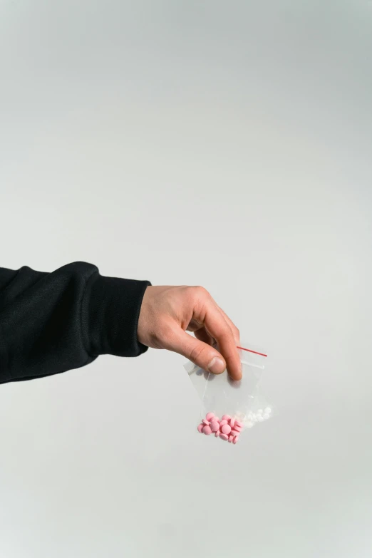 a close up of a person holding something in their hand, drugs, pink, pose 1 of 1 6, top-down shot