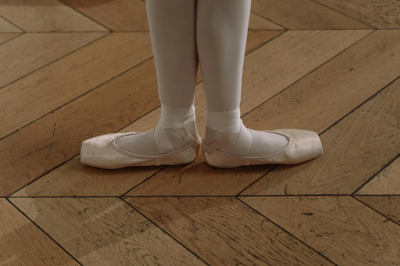 a little girl standing on top of a wooden floor, by Elsa Bleda, pexels contest winner, hyperrealism, ballet, realistic human feet, white, still from a wes anderson film