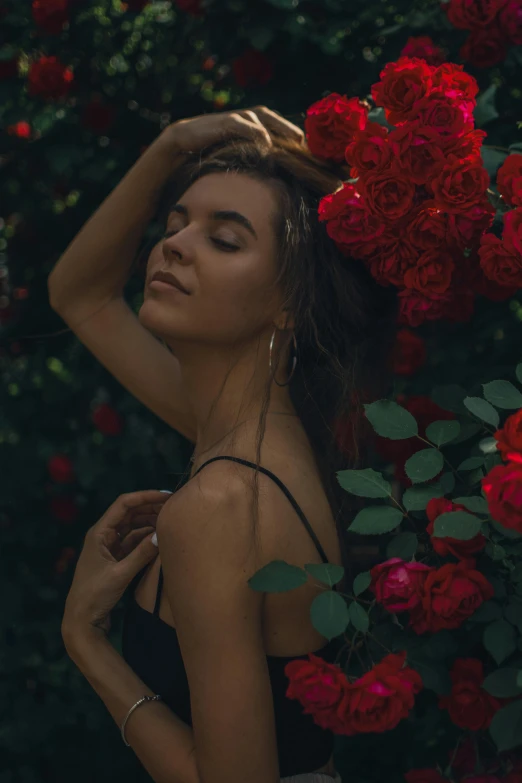 a woman standing in front of a bunch of red roses, inspired by Elsa Bleda, unsplash contest winner, romanticism, sunbathed skin, profile pose, slightly tanned, with black vines