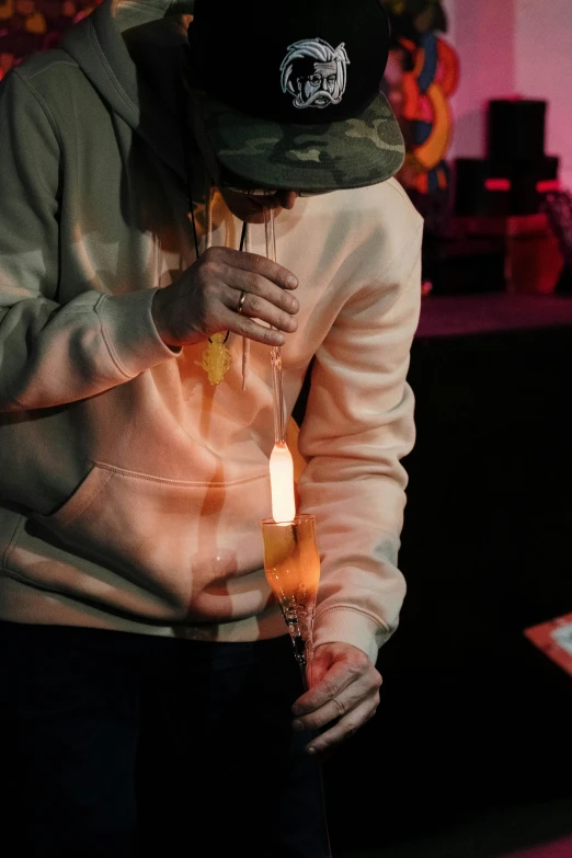 a man holding a lit candle in his hands, an album cover, inspired by Elsa Bleda, trending on pexels, in a hoodie, at a rave, smoky laboratory, with an iv drip