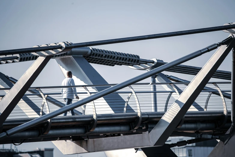 a man walking across a bridge on a sunny day, inspired by Zaha Hadid, happening, white mechanical details, steel and metal, 2022 photograph, trending on