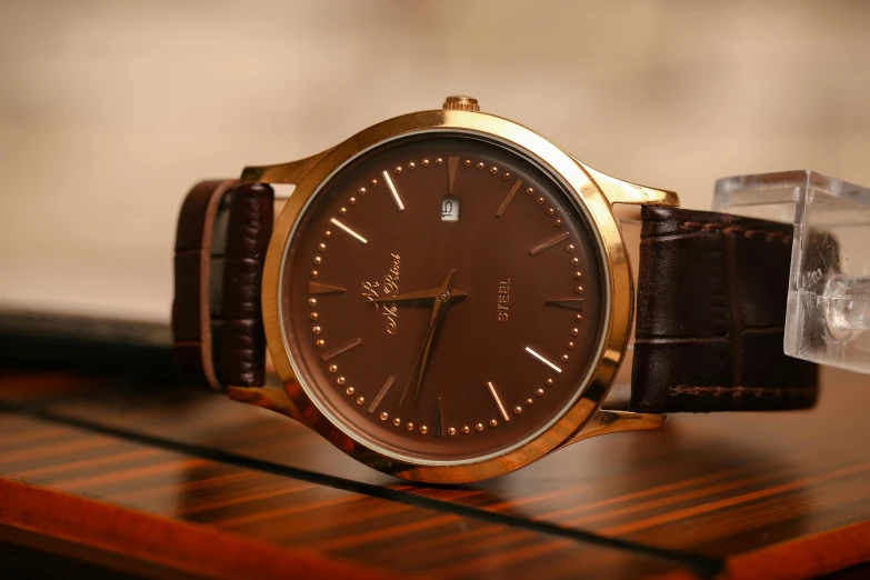 a close up of a watch on a table, an album cover, by Alejandro Obregón, trending on pixabay, brown and gold, formal attire, f / 1. 9 6. 8 1 mm iso 4 0, fully chocolate