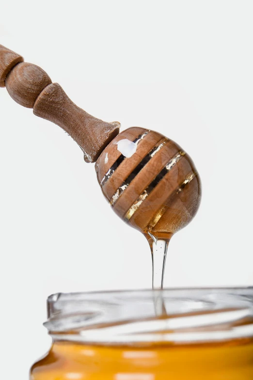 a wooden honey dipper sitting on top of a jar of honey, a digital rendering, by Ben Zoeller, trending on pexels, renaissance, made of glazed, close up shots, thumbnail, spoon placed