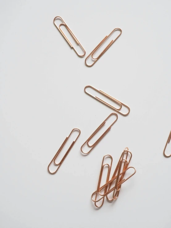 a bunch of paper clips laying on top of each other, by Matija Jama, rose gold, low detail, long, aykut aydogdu