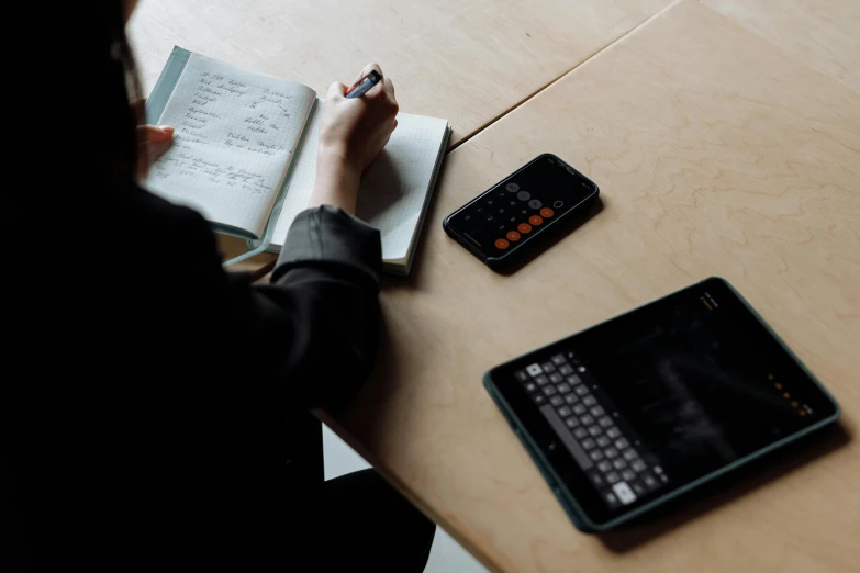 a person sitting at a table with a book and a calculator, trending on pexels, taken on iphone 1 3 pro, student, wetastudiofx, ergodox