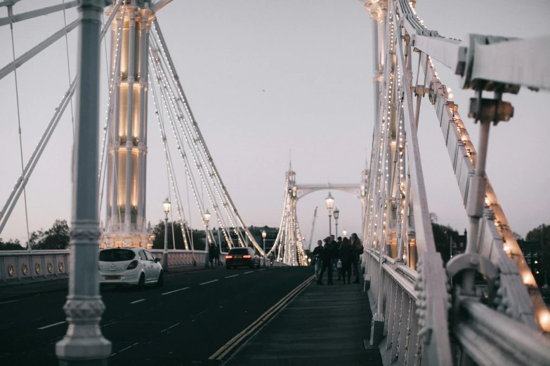 a group of people walking across a bridge, unsplash contest winner, aestheticism, white lights, seaside, lots of details, inside a grand