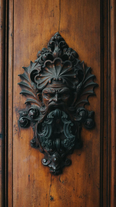 a close up of a door handle on a wooden door, inspired by Achille Leonardi, pexels contest winner, renaissance, green man, black and terracotta, face with beard, ornate furniture