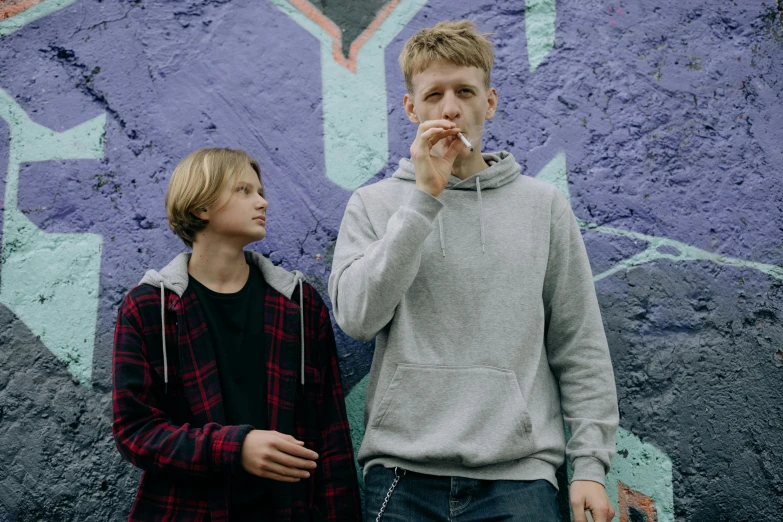 a couple of young men standing next to each other, an album cover, by Nick Fudge, pexels contest winner, graffiti, smoking a blunt, blond, press shot, concert
