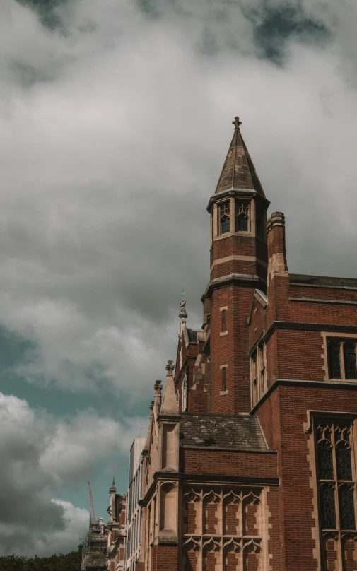 a large brick building with a clock tower, by IAN SPRIGGS, pexels, cloudy atmosphere, daniel oxford, holy cross, low quality photo