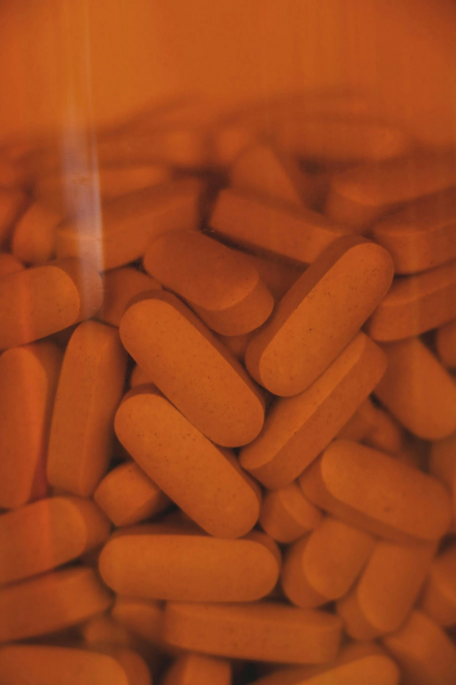 a jar filled with orange pills sitting on top of a table, by Adam Chmielowski, grainy quality, up-close, tubes, clay material