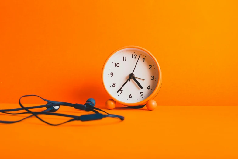 an orange alarm clock sitting next to a pair of headphones, trending on pexels, realism, avatar image, background image, 🦩🪐🐞👩🏻🦳, ultra realist