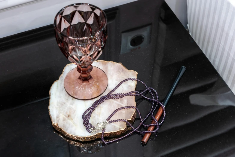 a glass vase sitting on top of a piece of wood, purple crystal jewelry, charcoal and champagne, holding wand, marble table