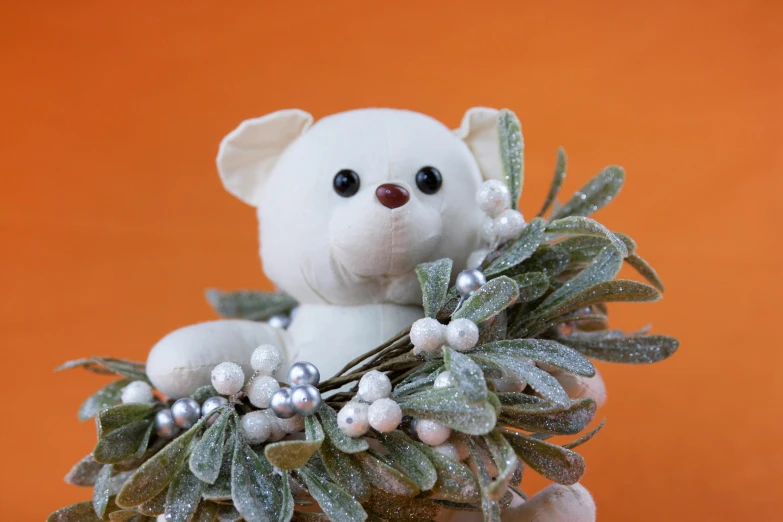 a white teddy bear sitting on top of a christmas wreath, inspired by Leo Leuppi, orange metal ears, evergreen branches, thumbnail, icy