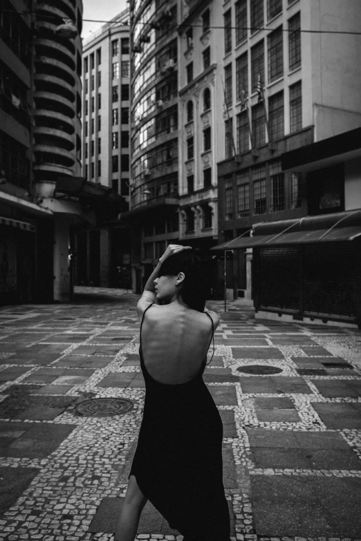 a black and white photo of a woman walking down a street, a black and white photo, unsplash contest winner, in sao paulo, full body cgsociety, beautiful lonely girl, bare back