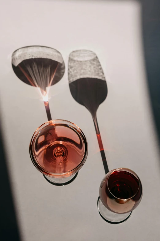 a couple of wine glasses sitting on top of a table, inspired by Méret Oppenheim, pexels contest winner, photorealism, pouring, pins of light, seen from below, spoon placed