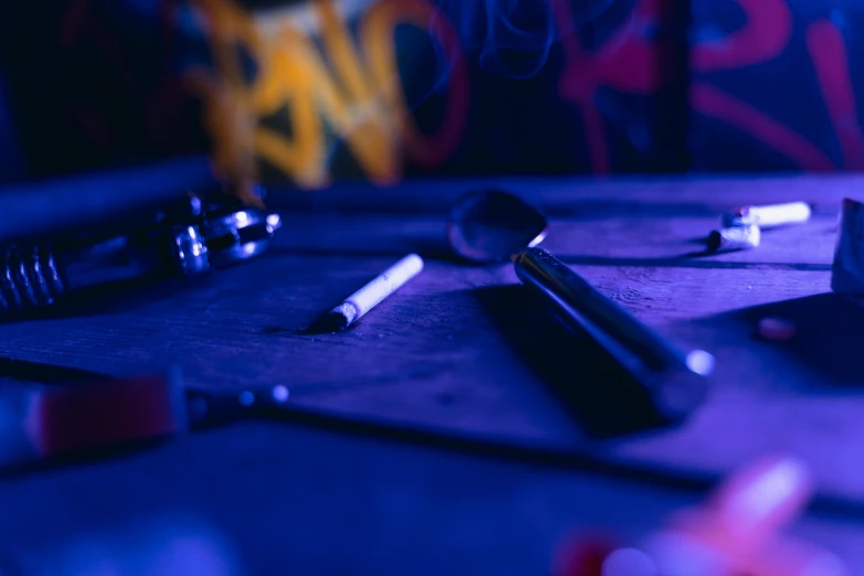 a bunch of tools sitting on top of a table, by Daniel Lieske, trending on pexels, graffiti, blue and purle lighting, detective, smoking, 15081959 21121991 01012000 4k