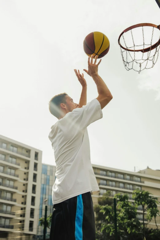 a man standing on top of a basketball court holding a basketball, playing games, zoomed out shot, outside, apartments
