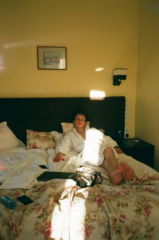 a woman laying on top of a bed in a bedroom, inspired by Nan Goldin, reddit, happening, sun behind him, low quality photo, tourist photo, in robes