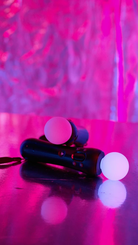 a pair of flashlights sitting on top of a table, inspired by Elsa Bleda, unsplash, interactive art, brightly lit pink room, spheres, controllers, programmable black goo