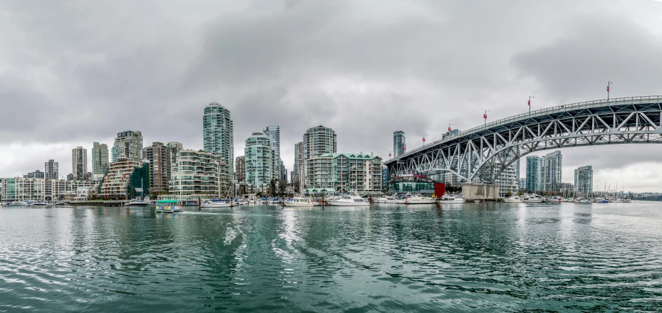 a bridge over a body of water with a city in the background, a photo, by Chris Rallis, pexels contest winner, vancouver school, overcast gray skies, boats in the water, wide angle ultra - vivid, slide show