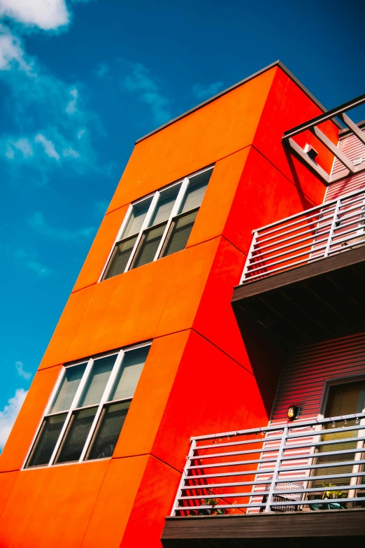 a red building with a balcony and balconies, inspired by Washington Allston, unsplash, modernism, vibrant orange, multicolored, low shot angle, multiple stories