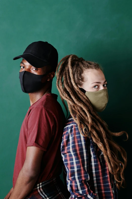 a man and a woman wearing face masks, a portrait, by Carey Morris, trending on pexels, dreads, green and black, schools, plain background