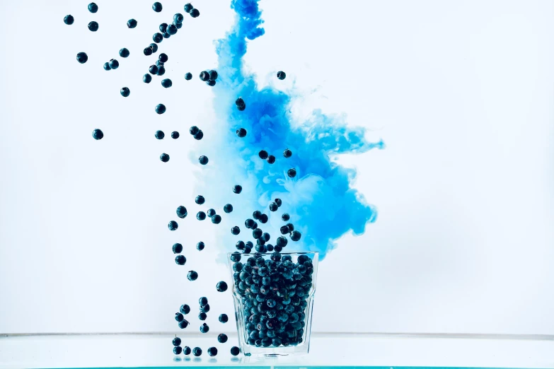 a glass filled with blue smoke and black balls, an album cover, inspired by Yves Klein, pexels, berries, toothpaste blast, blueberry, celebration