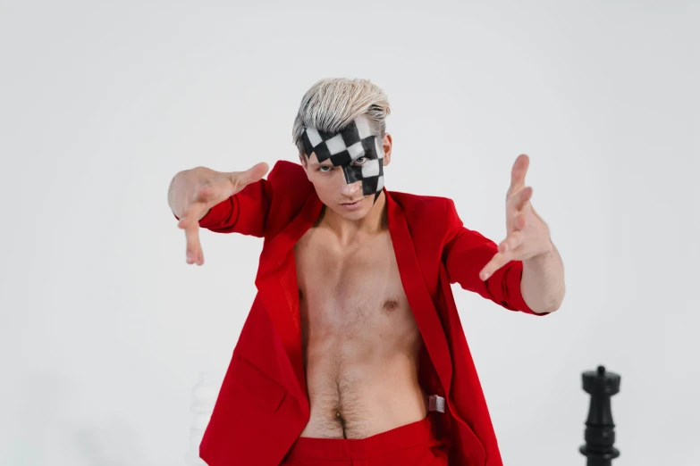 a man in a red suit standing next to a chess board, an album cover, inspired by Horace Vernet, trending on pexels, neo-dada, white hair floating in air, beefcake pose, cardistry, futuristic fashion show