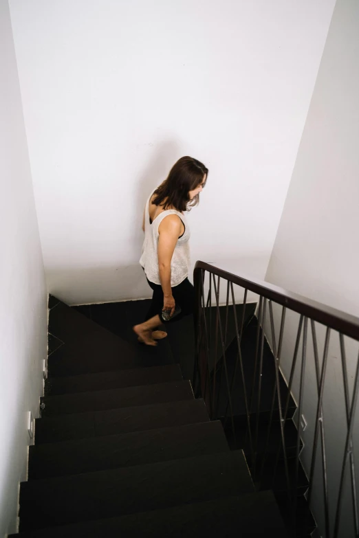 a woman walking up a flight of stairs, by Lucia Peka, pexels contest winner, happening, shy looking down, workout, standing in corner of room, lachlan bailey