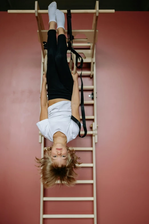 a woman hanging upside down on a ladder, by Nina Hamnett, trending on pexels, arabesque, top - down view, in a gym, 15081959 21121991 01012000 4k, petite girl