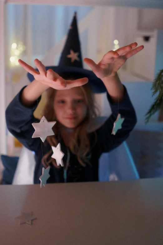 a little girl that is standing in front of a laptop, a hologram, pexels, magical realism, pentagrams, wearing festive clothing, hand on table, indigo magician