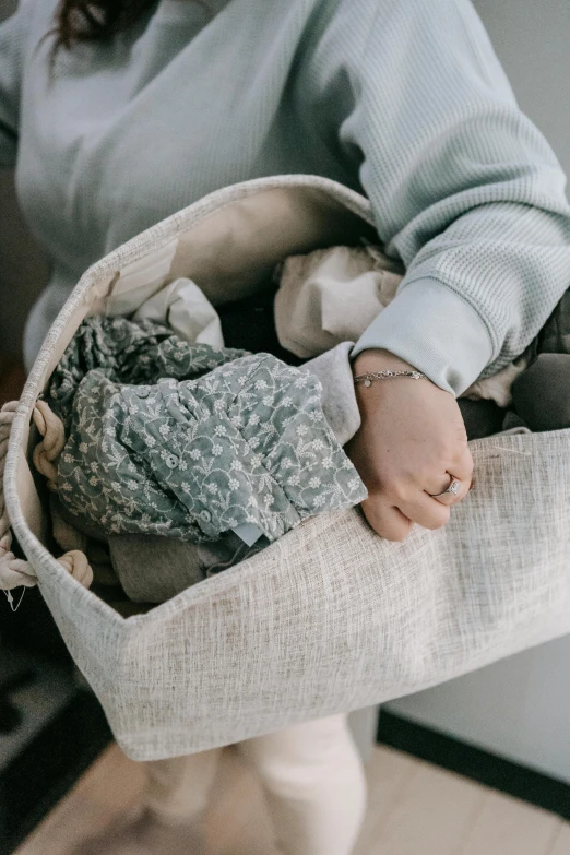 a woman holding a basket full of clothes, by Matija Jama, trending on unsplash, made of fabric, soft muted colors, little kid, grey