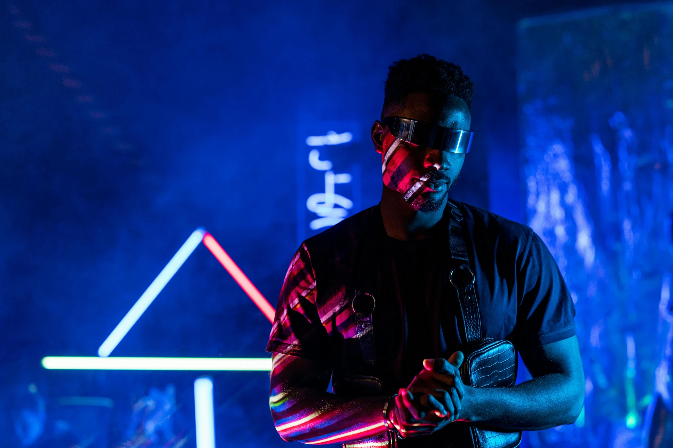 a man standing in front of a neon sign, pexels contest winner, afrofuturism, strobe and laser lights, techwear occultist, “house music rave with dancers, mkbhd