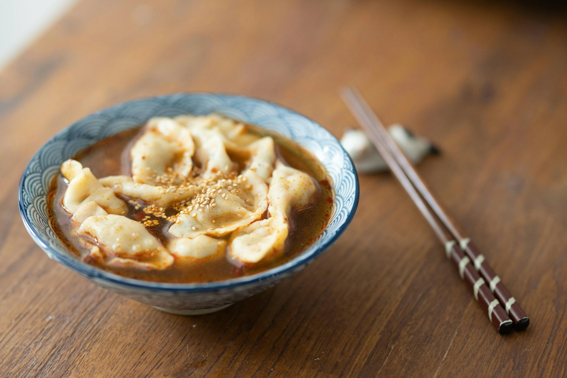 a bowl of soup and chopsticks on a table, unsplash, mingei, dumplings on a plate, square, brown, enamel