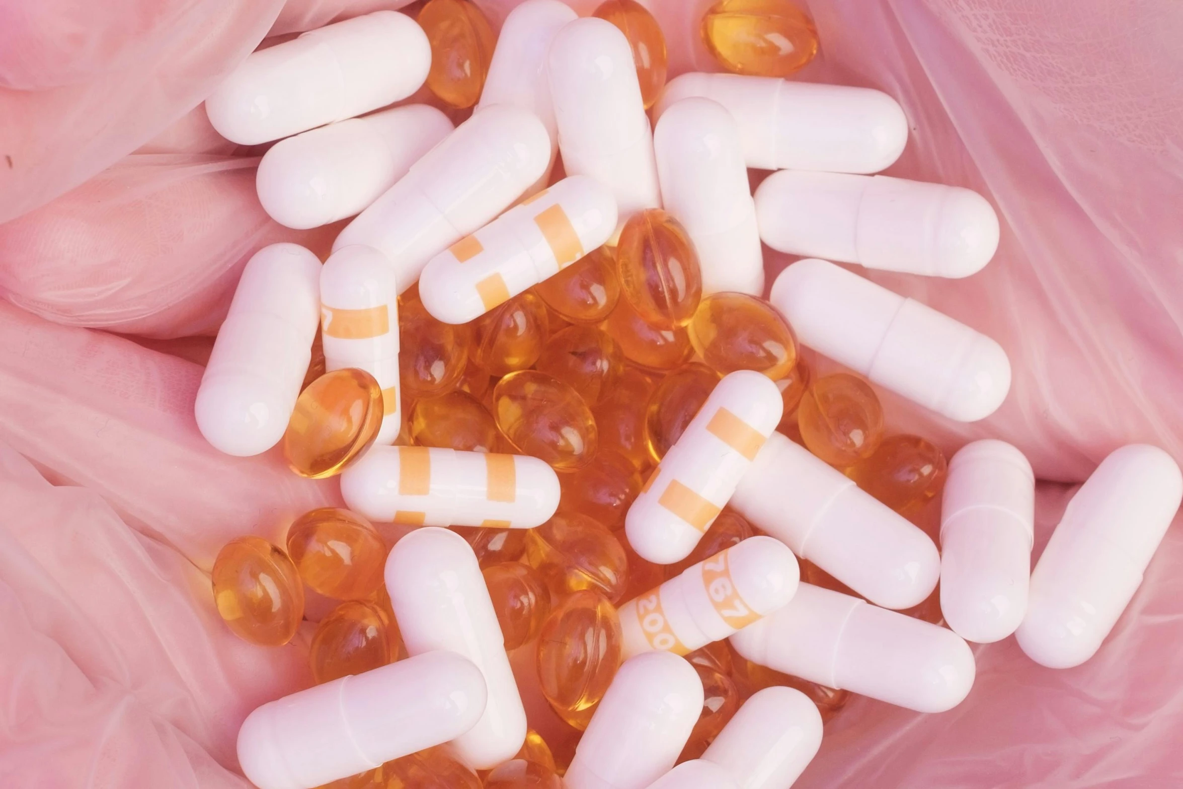 a close up of a person holding a bunch of pills, an album cover, unsplash, plasticien, toned orange and pastel pink, photorealism art, urine collection bag, open synthetic maw