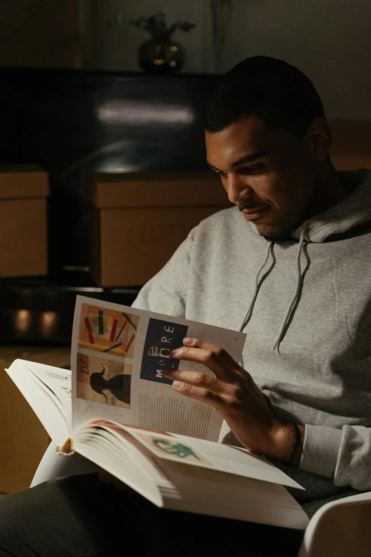 a man sitting in a chair reading a book, a picture, jayson tatum, commercial, jordan lamarre - wan, catalog
