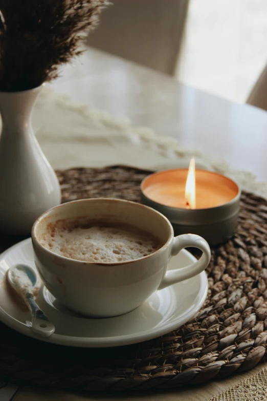 a cup of coffee and a candle on a table, trending on pexels, brown and cream color scheme, hispanic, serene, fan favorite