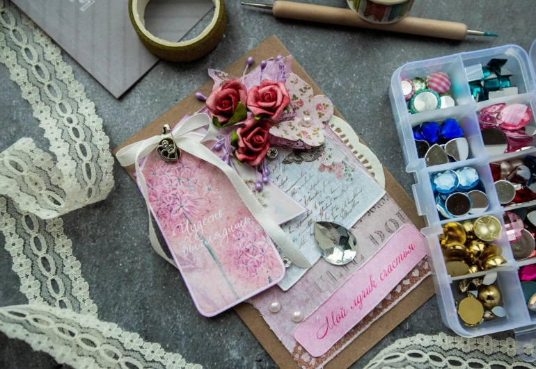 a box filled with assorted items sitting on top of a table, a picture, by Maksimilijan Vanka, pexels contest winner, mail art, delicate embellishments, pink color scheme, card template, whole card