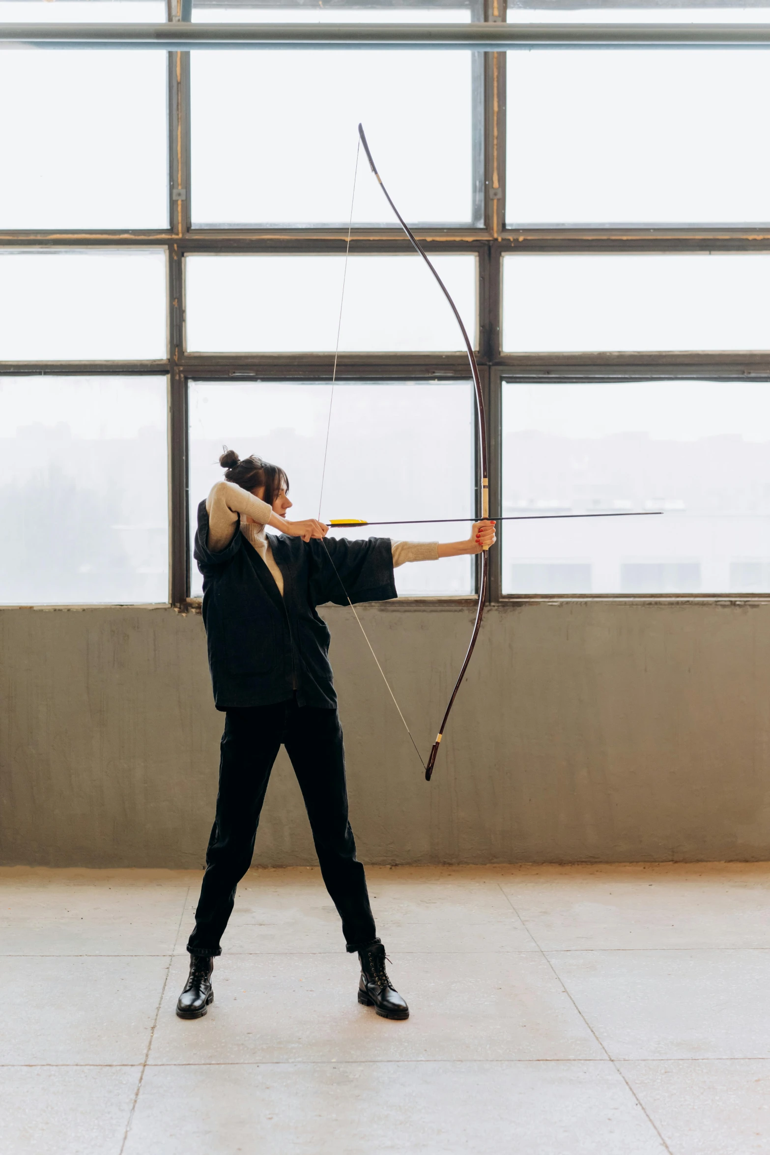 a man holding a bow and arrow in front of a window, by Marina Abramović, unsplash, arabesque, in an arena, louise zhang, sport, midcentury modern