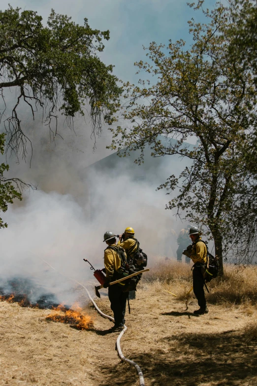 a group of firefighters standing on top of a grass covered hillside, pexels contest winner, renaissance, smoky laboratory, mexican standoff, talking around a fire, central california