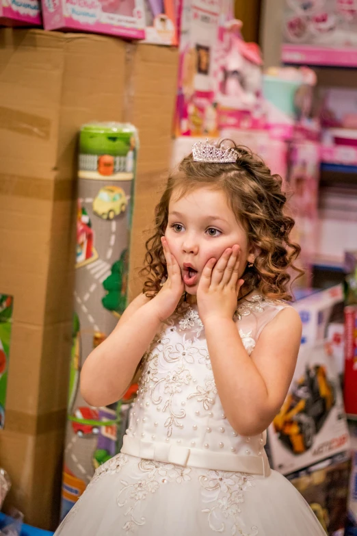 a little girl in a white dress standing in a store, pexels contest winner, happening, wearing a tiara, toy package, surprising, backdrop