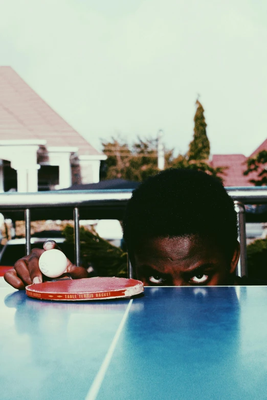 a person sitting at a table with a ping pong racket, an album cover, inspired by Gordon Parks, unsplash, happening, adebanji alade, eating outside, eyes, instagram picture